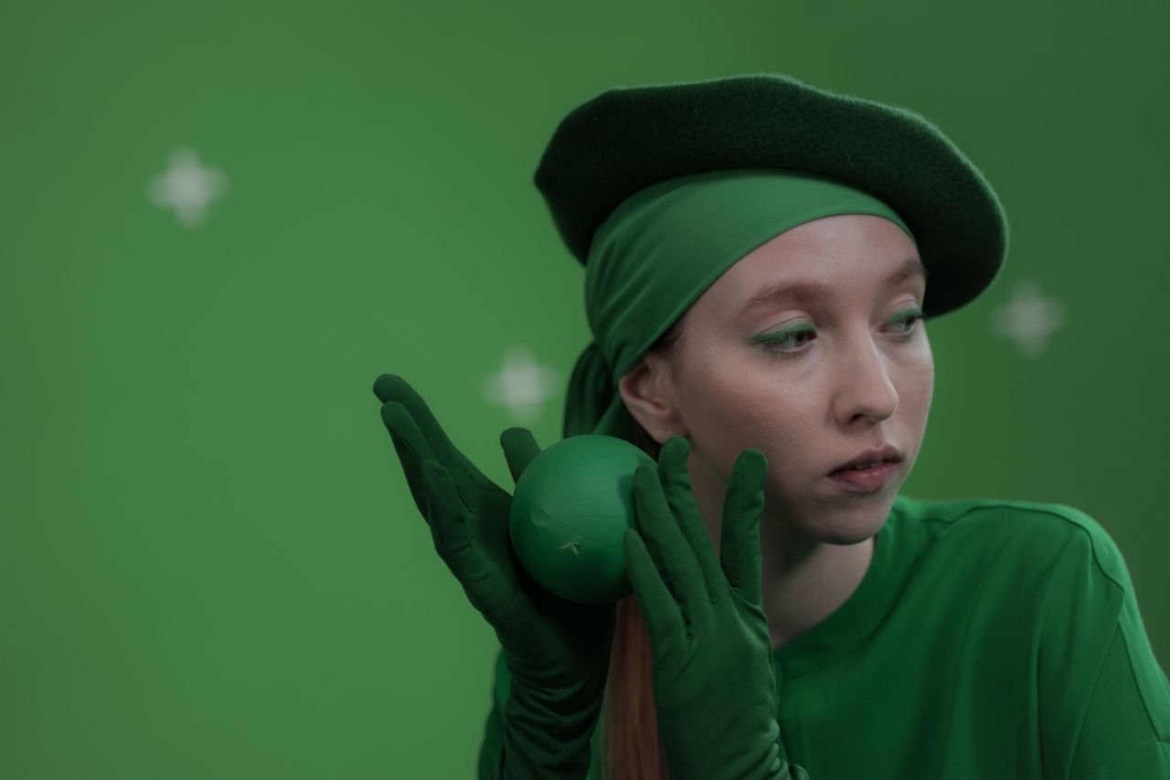 A woman in green attire poses with a ball, showcasing a monochromatic theme.